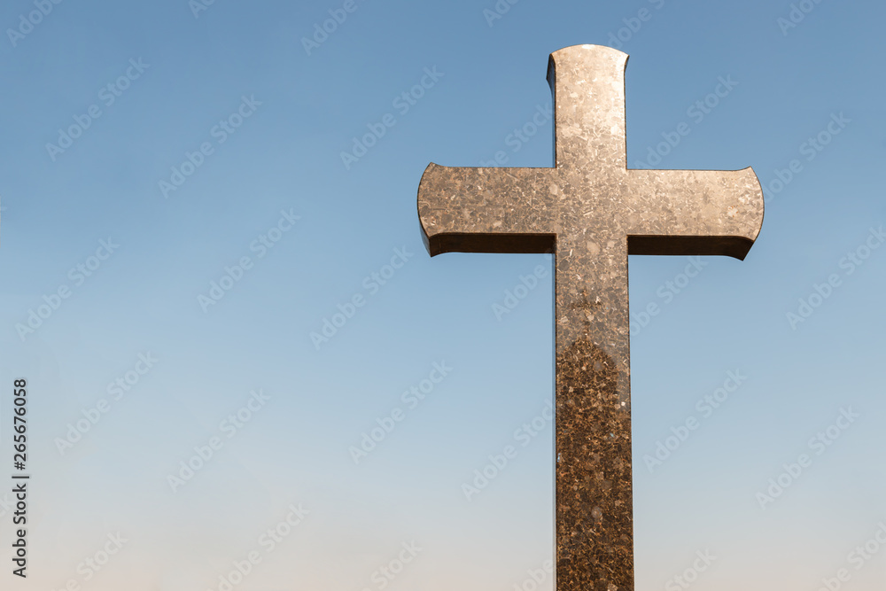 sunlight on granite cross against the blue sky, copy space for text. concept of Christianity. Granite cross on the sky background. sunlight on granite cross against the blue sky, copy space for text. concept of Christianity. Granite cross on the sky background.