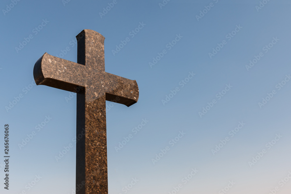 granite cross against the blue sky, copy space for text. Christianity faith and peace concept. granite cross against the blue sky, copy space for text. Christianity faith and peace concept.