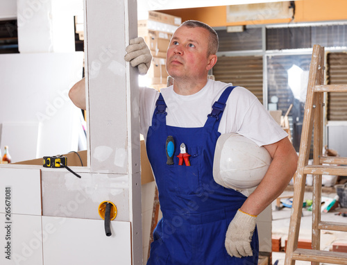 Tired builder leaning on wall photo