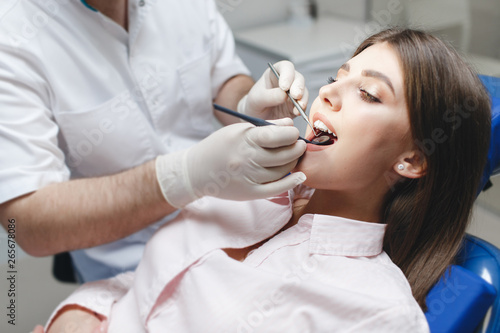 Dental clinic. Reception, examination of the patient. Teeth care. Young woman undergoes a dental examination by a dentist.Happy patient and dentist concept.Female dentist in dental office talking with