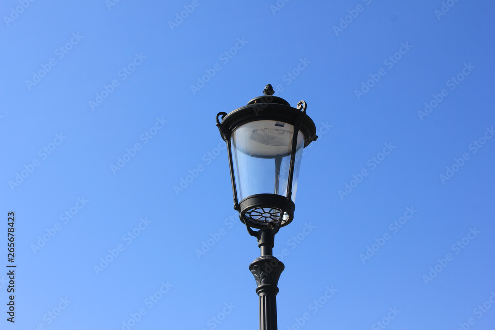 Old street lantern isolated on empty blue sky background. Retro lamp close up view Old street lantern isolated on empty blue sky background. Retro lamp close up view