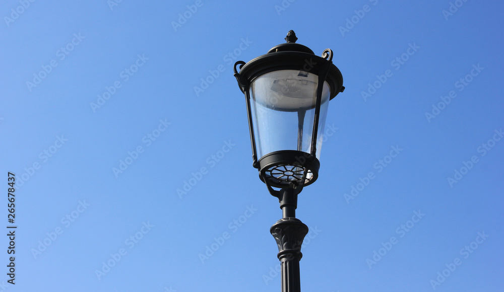 Lantern isolated on blue sky background.  Classic street lamppost with single light on summer day 