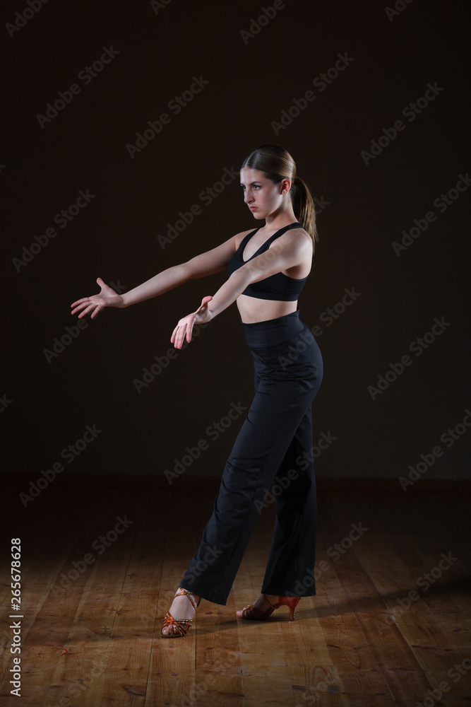 beautiful girl wearing black sportswear is training in the dance studio