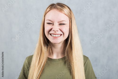 Portrait of a young beautiful laughing woman on a gray background.