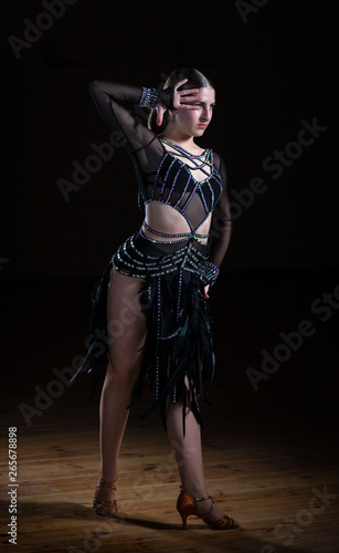 Fototapeta Naklejka Na Ścianę i Meble -  Beautiful Latino dancer girl in elegant black dress on black background