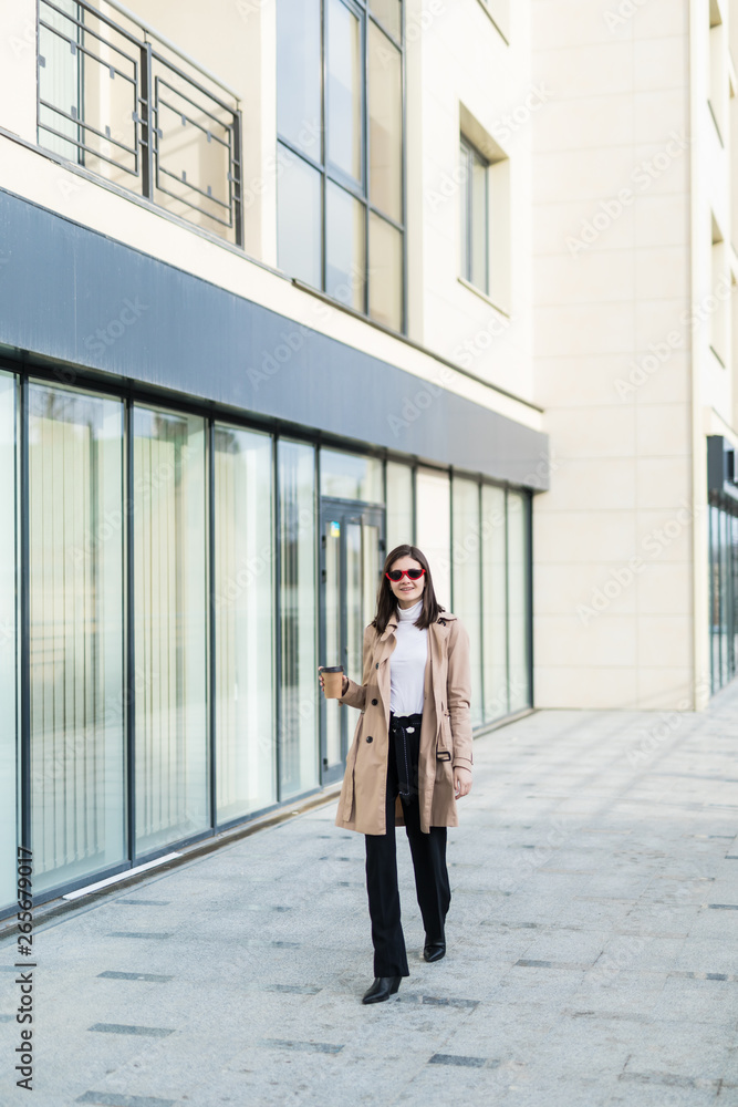 Beautiful brunette young woman in nice brown beige coat and sunglasses on urban background. Beautiful brunette young woman in nice brown beige coat and sunglasses on urban background.