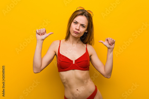 Young caucasian woman wearing bikini and sunglasses feels proud and self confident, example to follow.