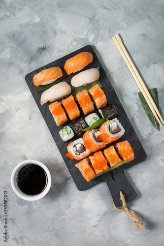 Various kinds of sushi rolls served on concrete background.