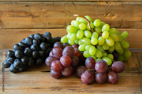 There different kinds of Grapes: green grape, red grape, dark grape on wooden background 