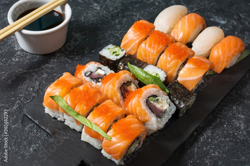 Various kinds of sushi rolls served on stone background.
