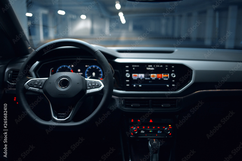 Modern car interior with multimedia and dashboard at underground parking. Luxury crossover at the empty parking lot