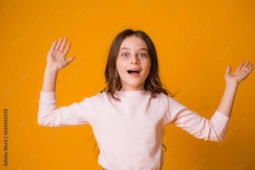 baby girl smiling surprised holding hands to face on yellow background