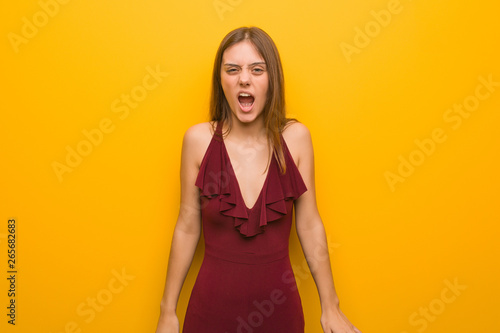 Young elegant woman wearing a dress screaming very angry and aggressive