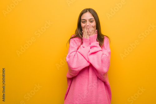 Young modern woman laughing about something, covering mouth with hands © Asier