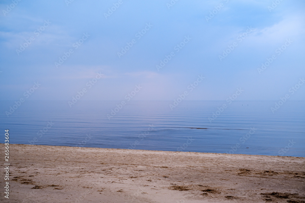 calm sea beach on the shore of Baltic sea with blue clouds and low tide