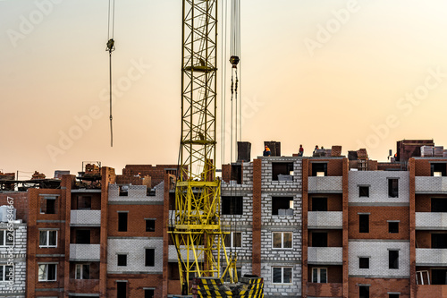 construction site with a multi-storey brick house and a tower crane in the evening