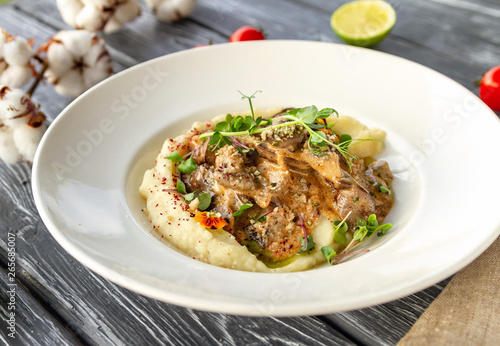 Chicken liver in creamy sauce with mushrooms and mashed potatoes, decorated with microgreen and flowers