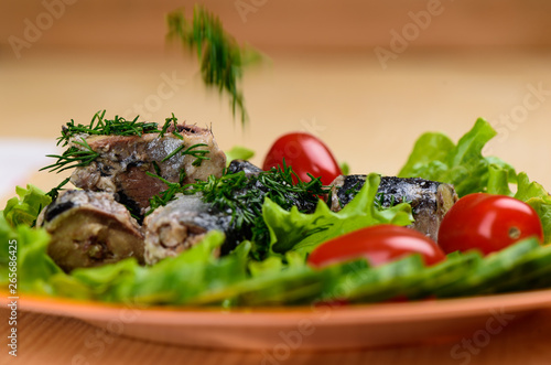 Pieces of sardine iwashi on lettuce leaves with red tomatoes. photo