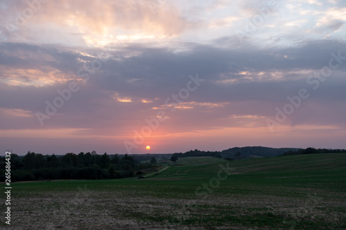 Evening scenery in the countryside, all the sky is in sunset colors and there is a red sun