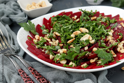 Healthy beetroot salad with peanuts and parsley on a white plate