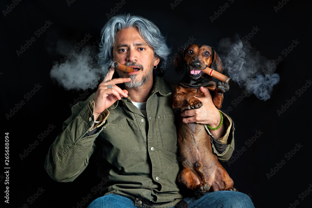 Studio portrait of man with dachshund smoking cigars