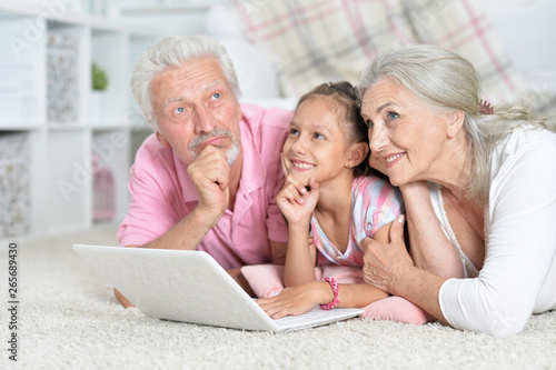 Grandparents with her granddaughter using laptop at home 