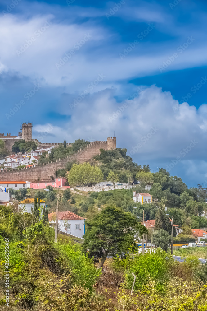 View of the fortress and Luso Roman castle of Óbidos, with buildings of Portuguese vernacular architecture and sky with clouds, in Portugal