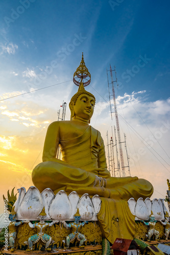 Golden Buddha statue on the top of the Wat Tham Sua or Tiger Cave Temple in Krabi province. Sunset sky