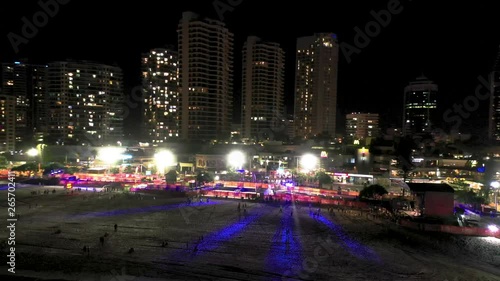 Low orbit aerial night shot of the a beach party in front of the coastal skyscrapers of Surfers Paradise in the Gold Coast Queensland Australia photo