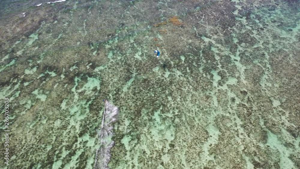 Kite surfing in clear water in the Indian ocean of Mauritius. High aerial view looking down on the surfer Kite surfing in clear water in the Indian ocean of Mauritius. High aerial view looking down on the surfer