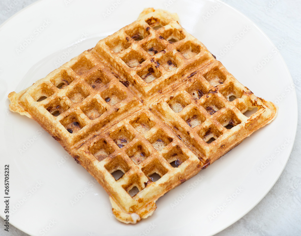 Homemade square belgian waffle on white plate Homemade square belgian waffle on white plate