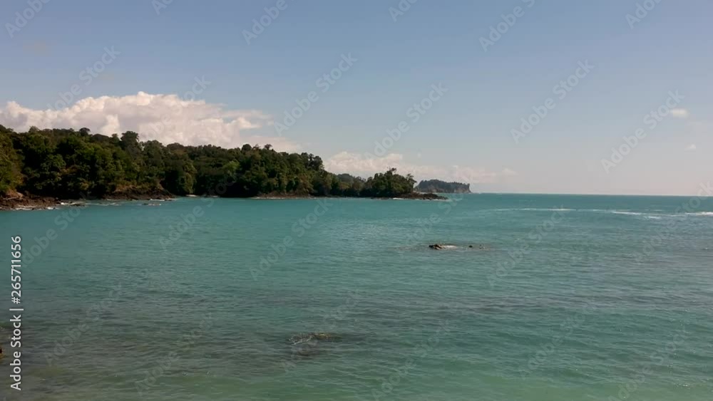 Aerial view of tropical turquoise sea water, jungle hills and blue sky background in Manuel Antonio national park, Costa Rica. Jib up dolly forward shot. Aerial view of tropical turquoise sea water, jungle hills and blue sky background in Manuel Antonio national park, Costa Rica. Jib up dolly forward shot.
