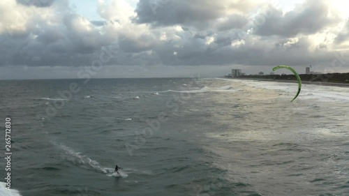 cinematic aerial video of kiteboarder riding towards the shore
