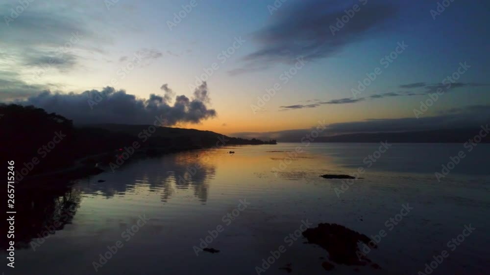 Aerial moving backwards over Isle of Mull coastline at sunset revealing silhouetted structures Aerial moving backwards over Isle of Mull coastline at sunset revealing silhouetted structures