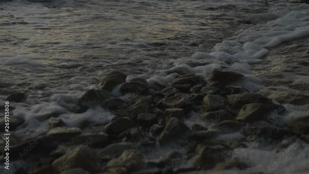 Moody slow motion shot of waves rolling in over small foreshore rocks during dusk. Moody slow motion shot of waves rolling in over small foreshore rocks during dusk.