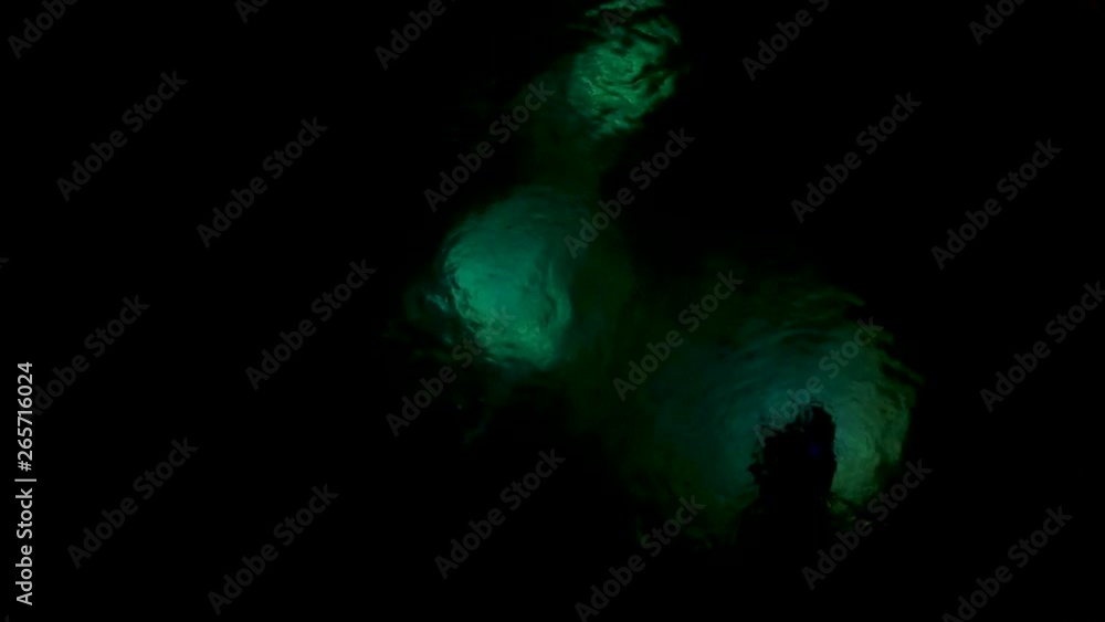 A group of scuba divers on a night dive with underwater lights A group of scuba divers on a night dive with underwater lights