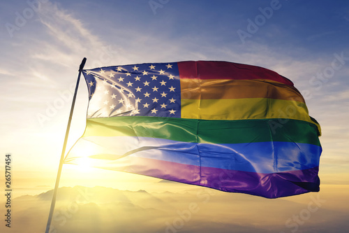 American flag stars gay pride rainbow flag waving on the top sunrise mist fog