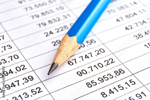 Blue pencil on a sheet of white paper with printed financial numerical data table with columns. Concept for accounting, budget, profit, tax and financial review. Image with selective focus    