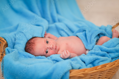 Beautiful little newborn baby 1 week lies in a basket with blue plaid. Portrait of pretty newborn baby.