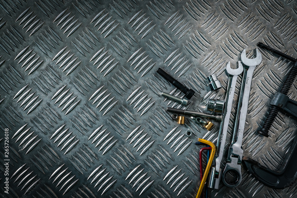 Fototapeta premium Top view of tools on industrial metal checker plate. Metal checkerplate for anti skid. Nut, bolts, and hex key on metal sheet floor. Silver bump ground with art pattern. Silver texture background.