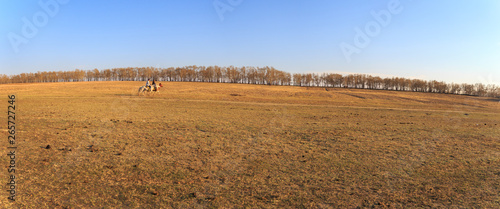 Panarama View of The grassland in early spring, A man riding horse at the grassland in Zhang Bei grassland, Heibei, China photo