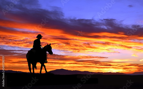 Cowboy on horseback rides into the sunset