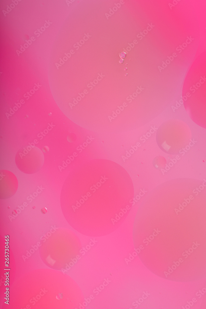 Blurred abstract background. Macro shot of oily liquid. Circles and wavy lines of different sizes of delicate pink color. Blur, vertical, a lot of free space for text, nobody, macro. Concept of design