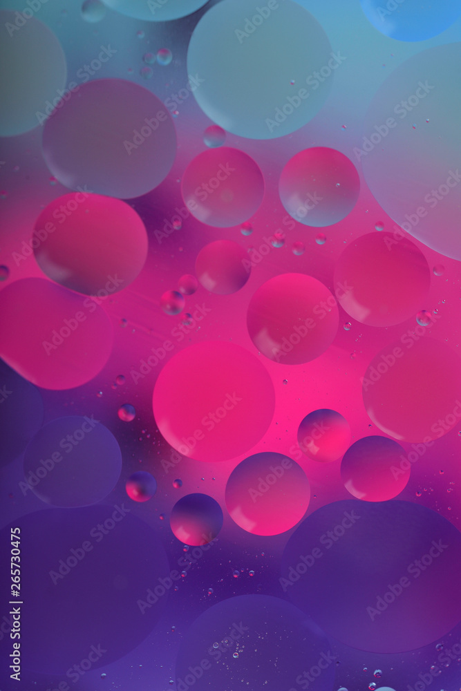 Blurred abstract background. Macro shot of oily liquid. Circles and wavy lines of different sizes in pink, violet and blue. Blur, vertical, a lot of free space for text, nobody, macro. Blurred abstract background. Macro shot of oily liquid. Circles and wavy lines of different sizes in pink, violet and blue. Blur, vertical, a lot of free space for text, nobody, macro.