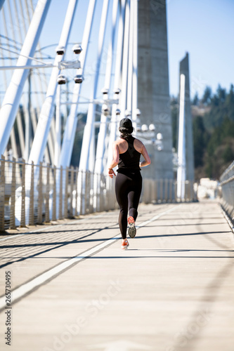 Girl in black tight sportswear trains run for weight loss on Tilikum Crossing Bridge