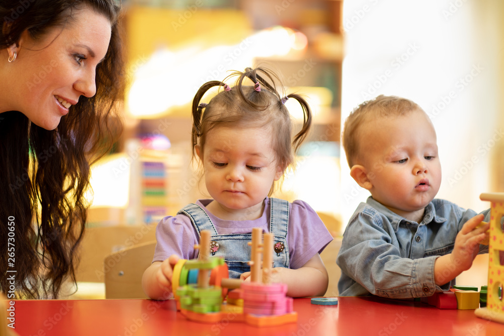 Teacher teaching kids play toy in classroom. Kindergarten pre school concept Teacher teaching kids play toy in classroom. Kindergarten pre school concept