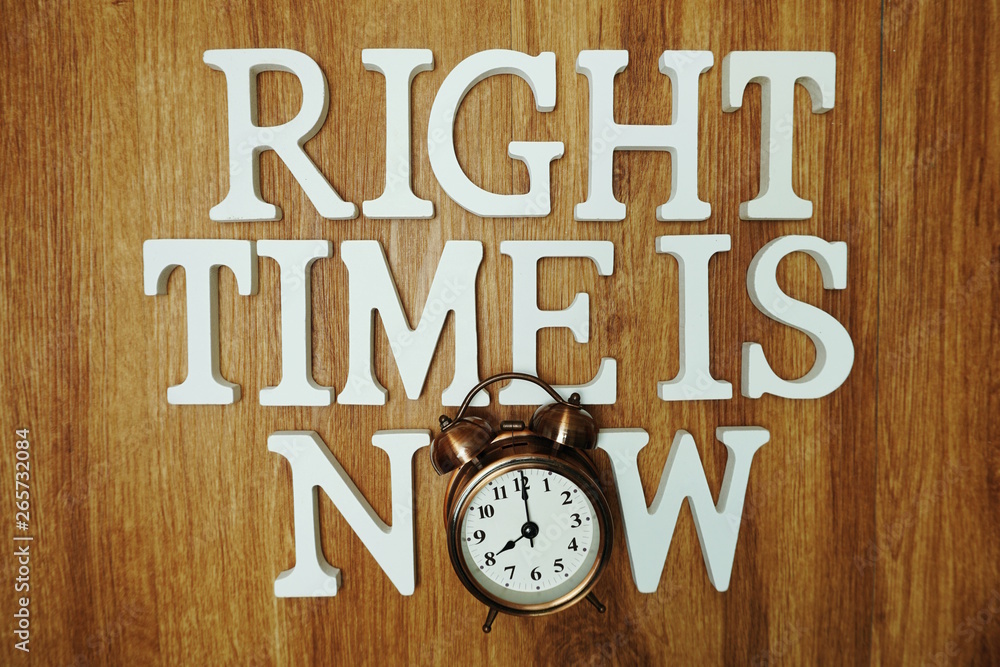 Right Time Time is Now alphabet letter with alarm clock on wooden background Right Time Time is Now alphabet letter with alarm clock on wooden background