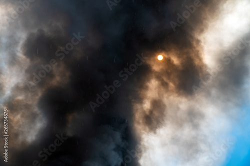 Thick black acrid smoke on the sky background