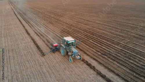 Agricultural spring campaign tractor with seeder sowing crops on farmer field. Hard rural job photo