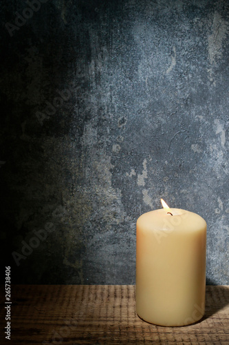 Single candle and dramatic lighting on grey stone background